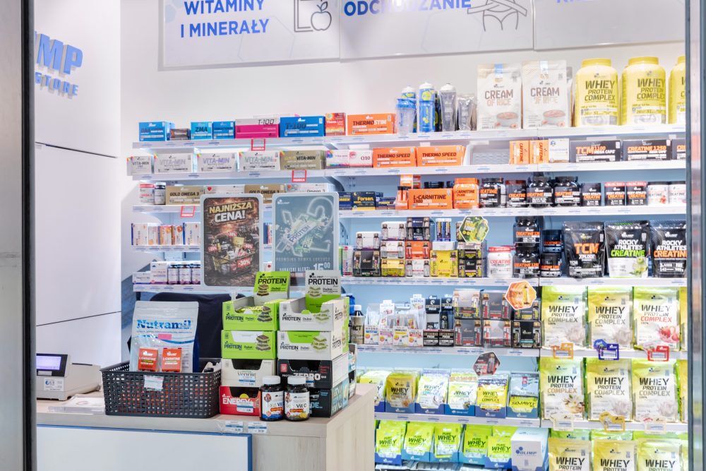 Nowoczesne wnętrze sklepu Olimp Store. Regały są uporządkowane i wypełnione szeroką gamą suplementów.