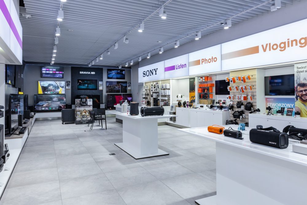 Perspektywa wnętrza Sony Centre ukazująca dział fotograficzny z aparatami na statywach oraz strefę gamingową z konsolami PlayStation 5.