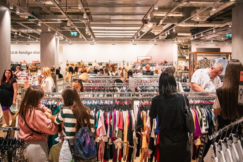 Wnętrze sklepu TK Maxx w Pasażu Grunwaldzkim. Widać szeroki wybór ubrań wiszących na wieszakach.