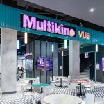 Widok na szerokie wejście do kina Multikino. Nad wejściem widoczne jest duże, podświetlane logo marki.
