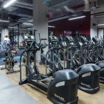 Rząd nowoczesnych orbitreków ustawionych w strefie cardio.