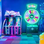 Kolekcja automatów typu arcade z klasycznymi joystickami i przyciskami. Widoczne maszyny do gier walki oraz flippery z bogato zdobionymi panelami graficznymi.