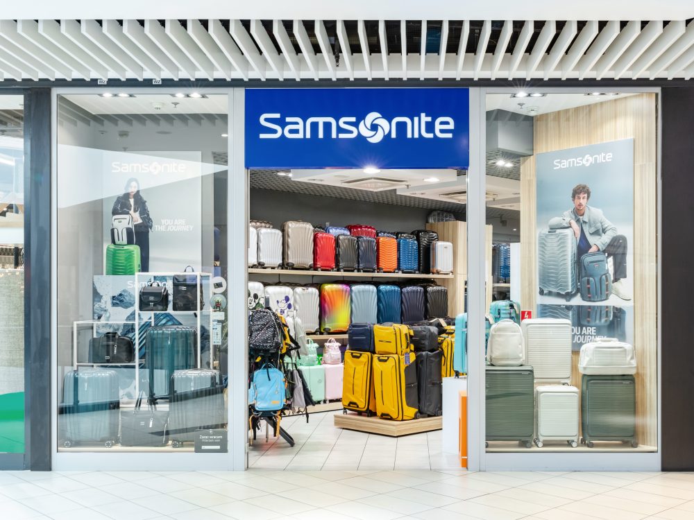 Widok na elegancki front salonu Samsonite. Nad wejściem widoczne jest prestiżowe, podświetlane logo marki.