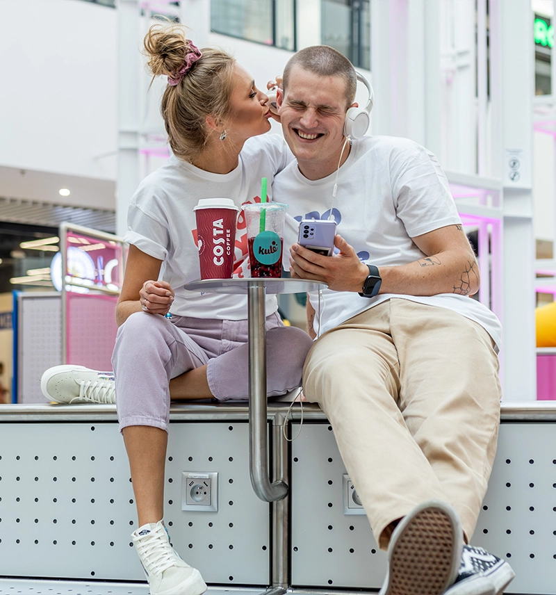 para siedząca w pasażu grunwaldzkim słuchająca muzyki śmiejąca się
