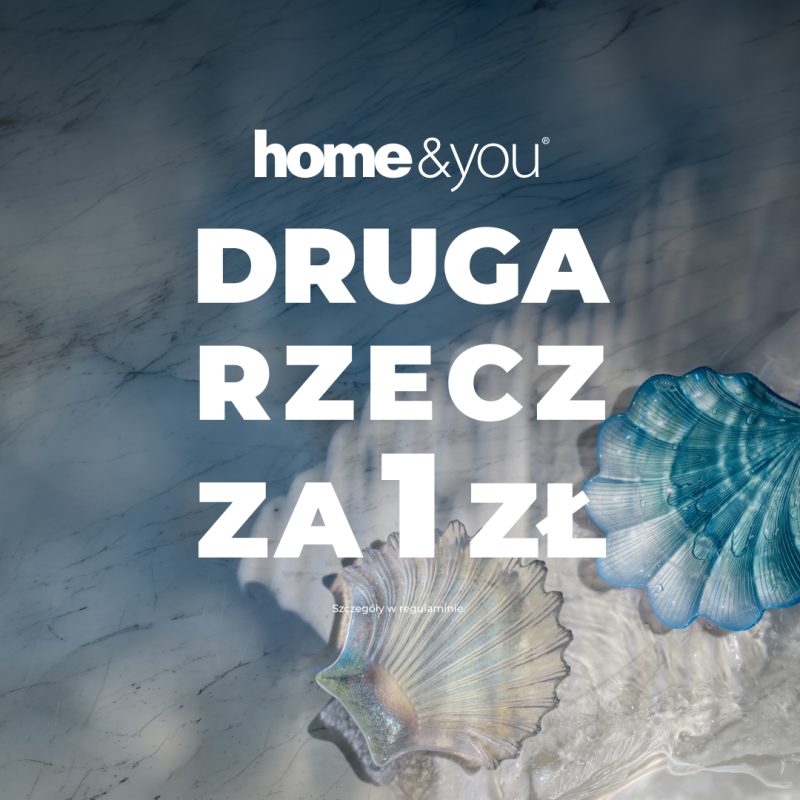 Grafika promuje akcję sprzedażową w salonach Home&You pod hasłem „Druga rzecz za 1 zł”. Duży, biały napis umieszczono na tle artystycznego zdjęcia przedstawiającego dekoracyjne muszle zanurzone w wodzie na marmurowym podłożu.