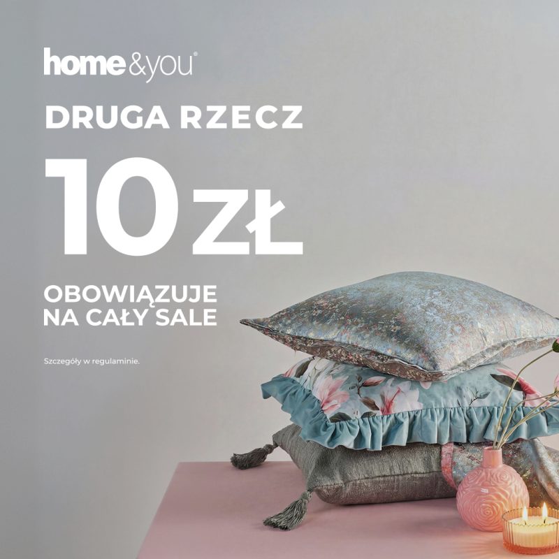 Trzy dekoracyjne poduszki ułożone jedna na drugiej – szara, błękitna w kwiaty z falbaną oraz połyskująca niebieska – obok różowego wazonu i zapalonej świeczki w szkle. W tle napisy home and you Druga rzecz 10 zł obowiązuje na cały sale.