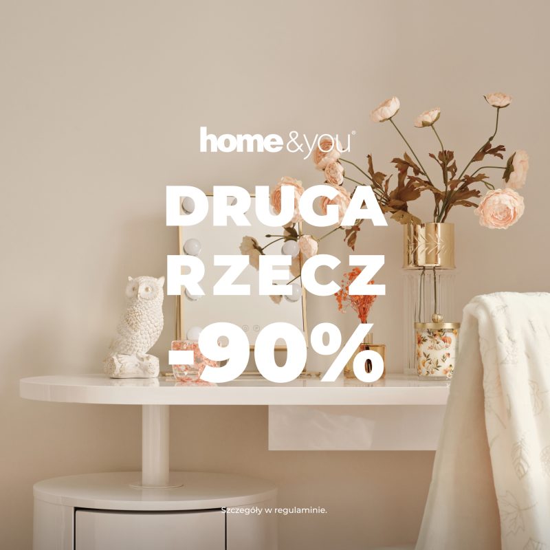 Baner promocyjny marki home&you z hasłem „DRUGA RZECZ -90%”. Na zdjęciu przedstawiono białe toaletki ze stylowymi dodatkami: figurką sowy, wazonem z kwiatami i podświetlanym lusterkiem.