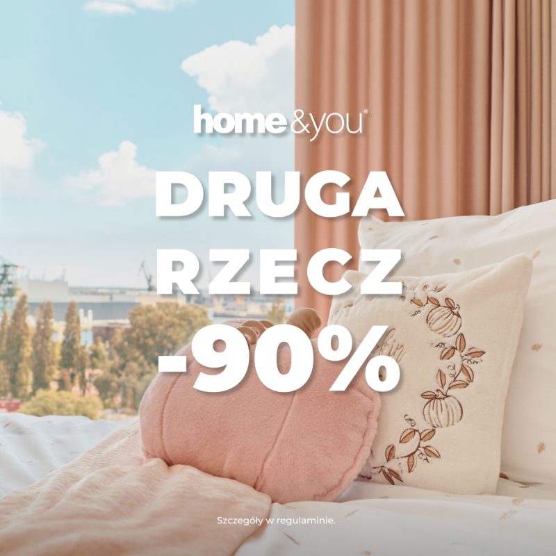 Kwadratowe zdjęcie promocyjne marki home&you pokazujące jasny i przytulny kadr sypialni. Na łóżku ułożona jest wzorzysta pościel, różowa narzuta oraz dekoracyjne poduszki w kształcie dyni. W tle widać okno z miejskim widokiem oraz beżową zasłonę. Na środku umieszczono logo home&you oraz napis DRUGA RZECZ -90%.