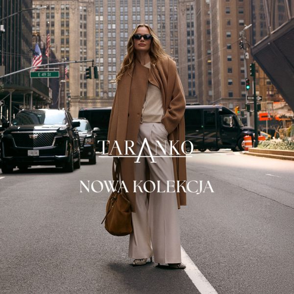Elegancka grafika promocyjna nowej kolekcji marki Taranko w miejskim stylu. Na pierwszym planie widać modelkę w okularach przeciwsłonecznych, beżowym płaszczu zarzuconym na ramiona, jasnych spodniach z szerokimi nogawkami oraz z brązową torbą, stojącą na ulicy dużego miasta. W centralnej części grafiki znajduje się biały napis z nazwą marki „TARANKO” oraz hasło „NOWA KOLEKCJA”. W tle widoczna jest miejska zabudowa z wieżowcami i samochodami.